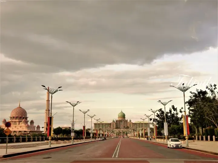 Wide avenue leading to the green-domed Putra World Trade Centre and pink Putra Mosque in Putrajaya, Malaysia.