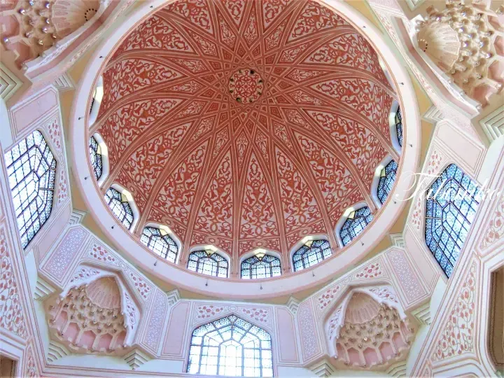 Ornate pink and white dome ceiling with intricate geometric patterns and stained glass windows at The Suria KLCC.