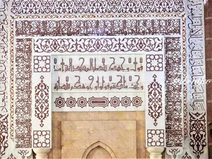 Intricate Arabic calligraphy and geometric patterns adorning a mosque wall in Malaysia.
