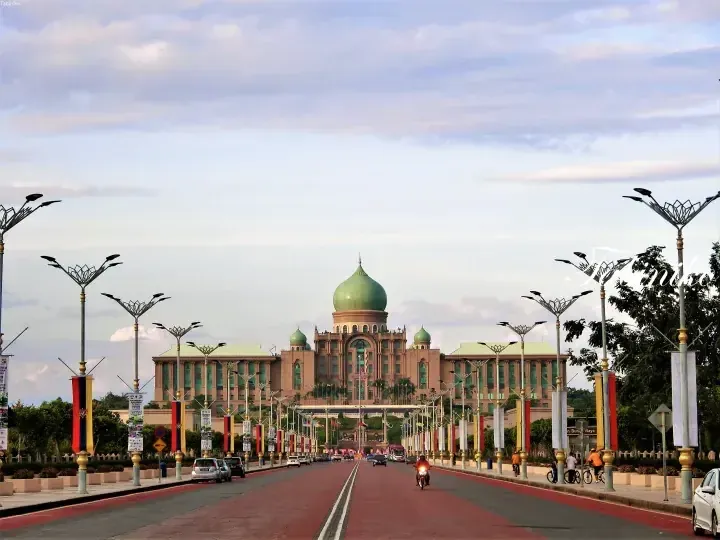 The iconic Putra Mosque with its green dome stands majestically at the end of a wide boulevard in Putrajaya, Malaysia.