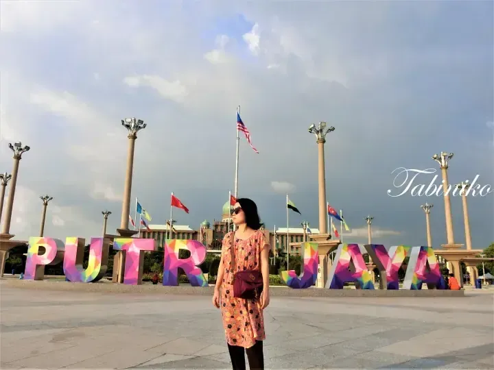 Woman posing in front of colorful Putrajaya letters with the Prime Minister’s Office in the background.