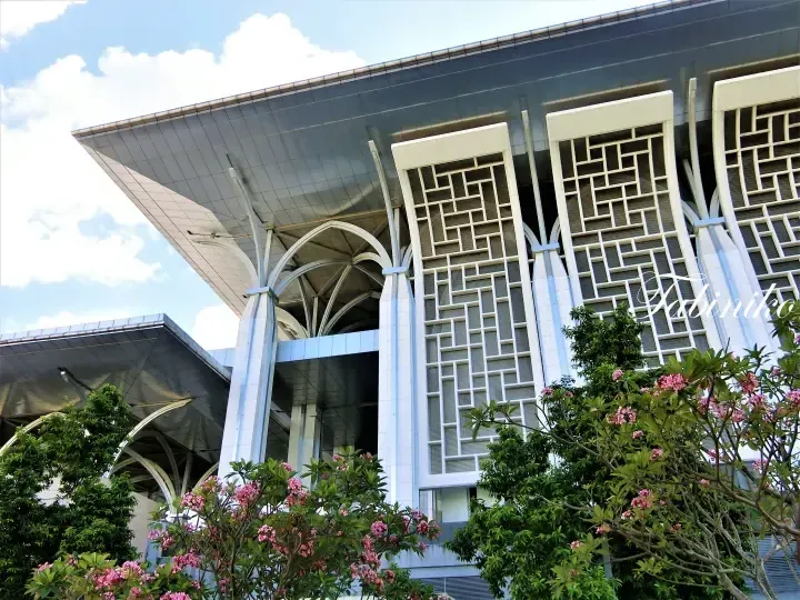 Modern architecture with geometric patterns and pink flowers at the foreground of a building in Malaysia