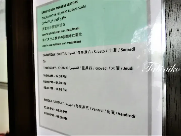 Sign indicating opening hours for non-Muslim visitors at a mosque in Malaysia, listing times for Thursday, Friday, and Saturday.