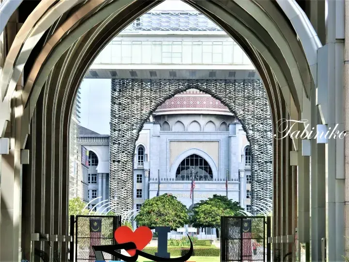 I Love KL heart sculpture viewed through an archway framing the Istana Kehakiman building in Putrajaya.