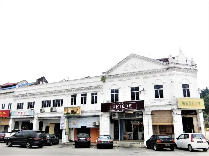 A row of white heritage shophouses featuring Lumière Café and Master store in Malaysia.