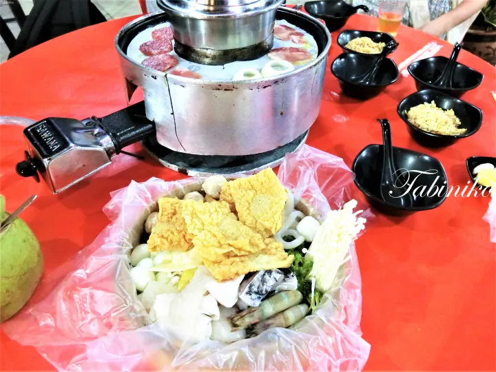 赤いテーブルに並ぶ、新鮮な海鮮や野菜、肉を使った伝統的なマレーシアの火鍋。