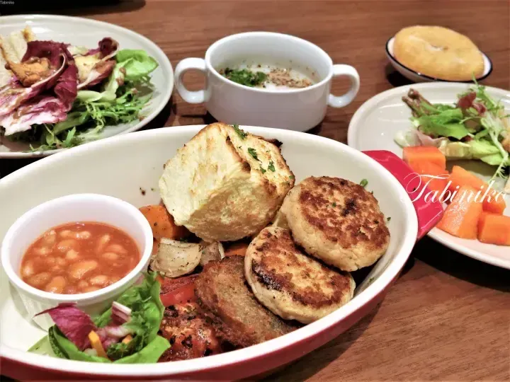 A hearty breakfast spread featuring grilled fish patties, baked beans, toast, and fresh salad on a wooden table.