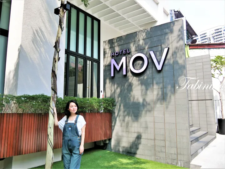 モダンな外観と緑に囲まれたマレーシアのHotel MOVの外でポーズをとる女性。