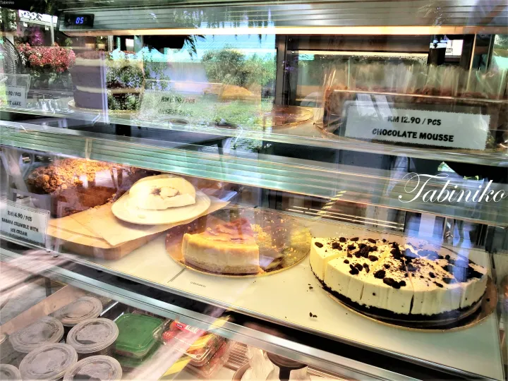 マレーシアのカフェで、チョコレートムースやバナナクラムブルなど様々なケーキが並んだ冷蔵ショーケース。