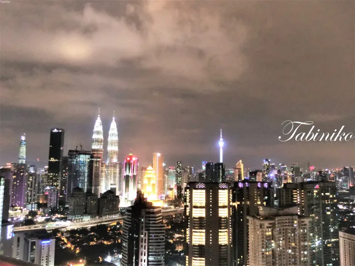 雲がかかる空に照らされたKLタワーとペトロナスツインタワーズを映すクアラルンプールの夜景。