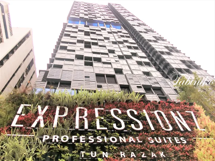 緑豊かな壁に大きな看板が設置されたExpression Professional Suites Tun Razakの外観。