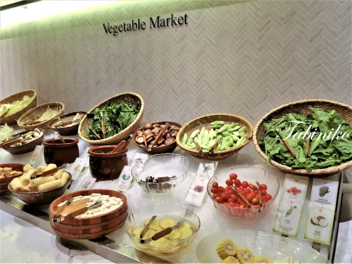 Vegetable Market buffet display featuring fresh produce in woven baskets and bowls on an ice bed.