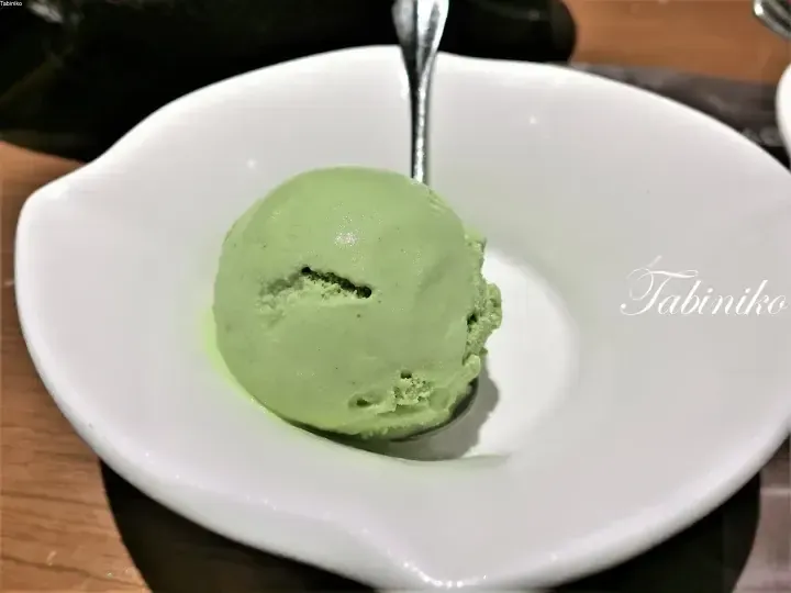 白いボウルに盛られた緑色の抹茶アイスクリームとスプーン。