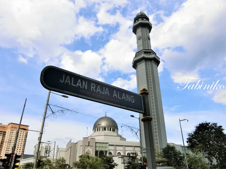 クアラルンプールのJalan Raja Alangの街路標と銀色のドームを持つMasjid Jamek。