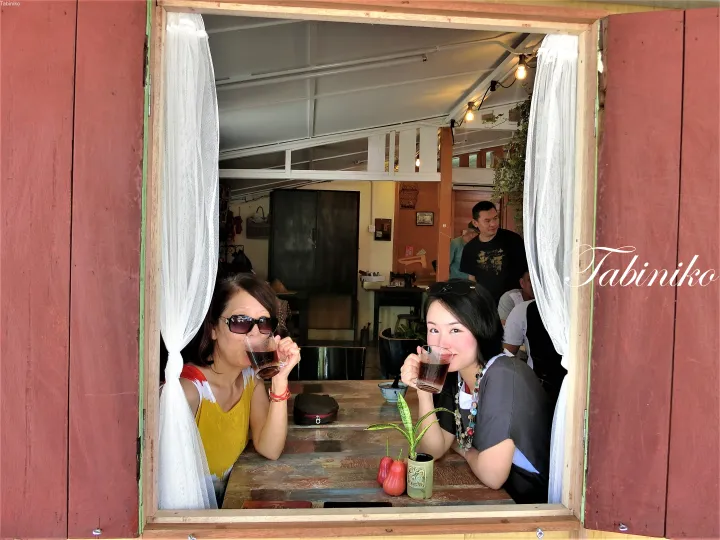 マレーシアのカフェで木製の窓から飲み物を楽しむ二人の女性。