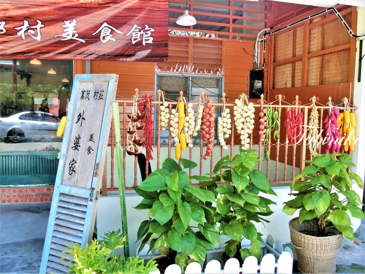 乾燥野菜が飾られた万茂村荘の外観と木製看板。