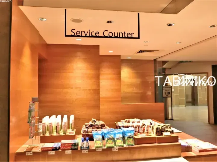 Service Counter display at a hotel featuring Colgate toothpaste, tissues, and toiletries on wooden shelves.