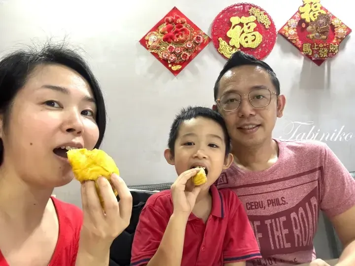 A family enjoys eating durian in front of festive Chinese New Year decorations.