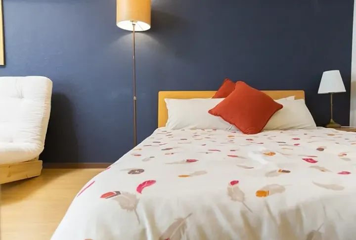Cozy bedroom with blue walls, wooden bed, and feather-patterned duvet