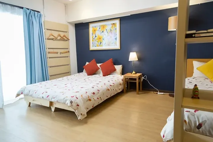 Bright bedroom with blue accent wall, floral bedspread, and wooden furniture in a modern Malaysian rental property