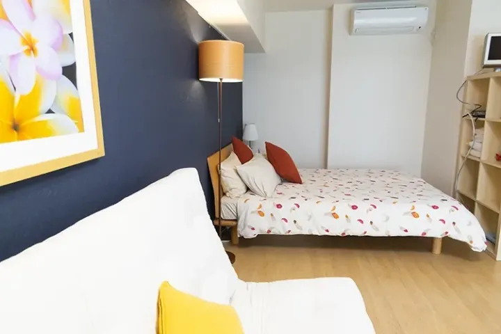 Cozy bedroom with a floral bedspread, blue accent wall, and modern furnishings.