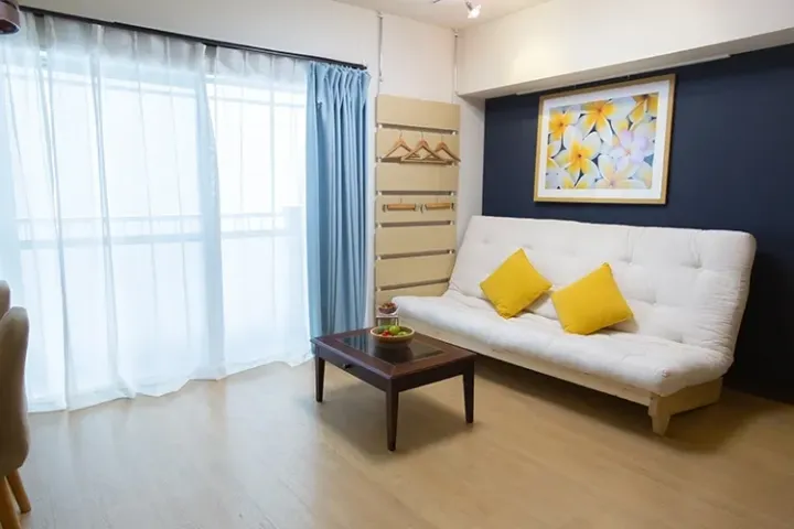 Bright living room with white sofa, yellow cushions, and blue curtains in a modern apartment.