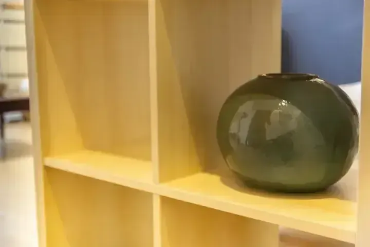 現代室內淺色木製層架上擺放著一個綠色陶瓷花瓶。