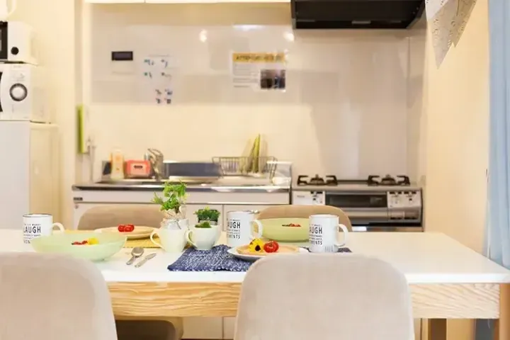 朝食がセットされたダイニングテーブルとモダンなキッチンが映る明るいアパートの室内。