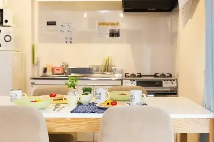 明亮公寓內設有現代廚房，餐桌上擺放著早餐、白色馬克杯和新鮮水果。