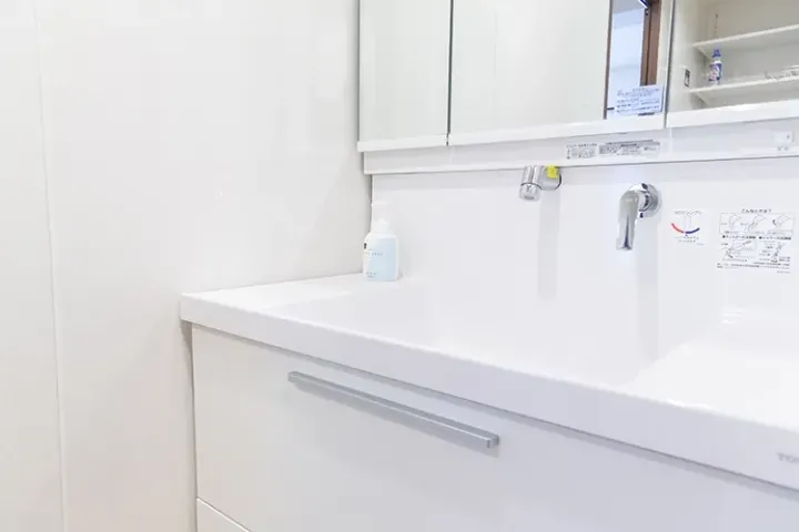 Modern white bathroom vanity with sink, chrome faucet, and medicine cabinet in a clean residential setting.