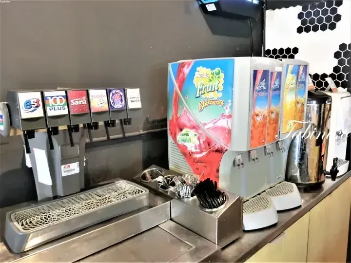 Self-service beverage station with Nescafe Fruit and Nestea dispensers, soda machines, and condiments at a modern property.
