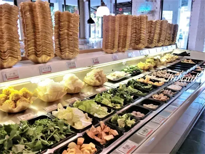 Buffet display featuring stacks of golden wonton wrappers and fresh vegetables in a restaurant setting