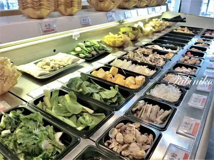 ビュッフェレストランで黒いトレイに並べられた新鮮な野菜、コーン、海鮮。