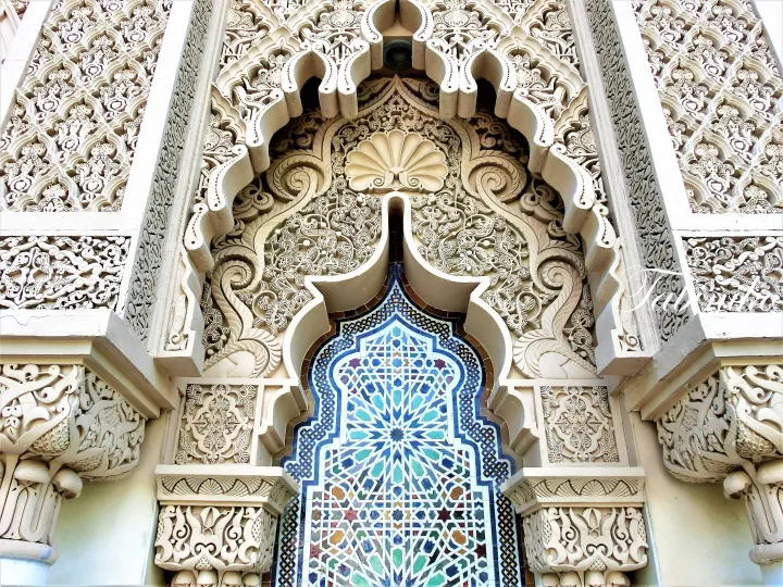 Intricate Islamic architectural details featuring ornate stucco carvings and a colorful geometric tile archway.