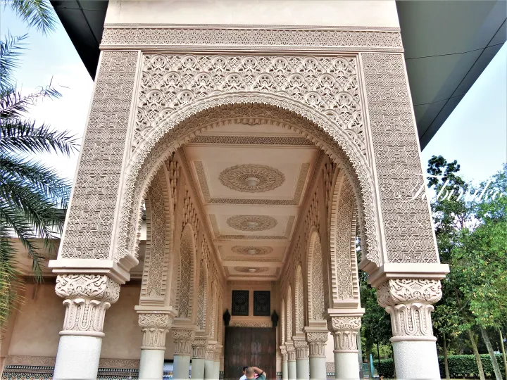 Ornate Moorish archway entrance at the Blue Mosque in Kuala Lumpur, Malaysia, featuring intricate geometric carvings and decorative columns.