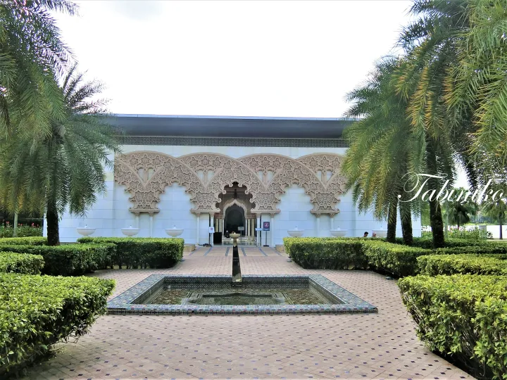 Ornate Moorish arches and a tiled fountain at the entrance of Putra Mosque in Putrajaya, Malaysia