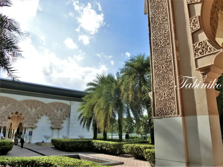 Ornate Moorish arches and detailed stonework at a Malaysian resort garden with palm trees under a blue sky