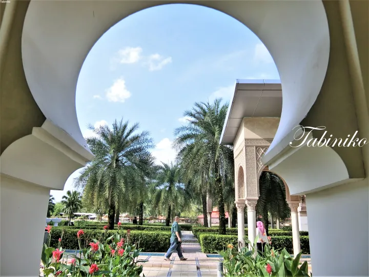 View of lush tropical gardens framed by a white archway at a resort in Malaysia.