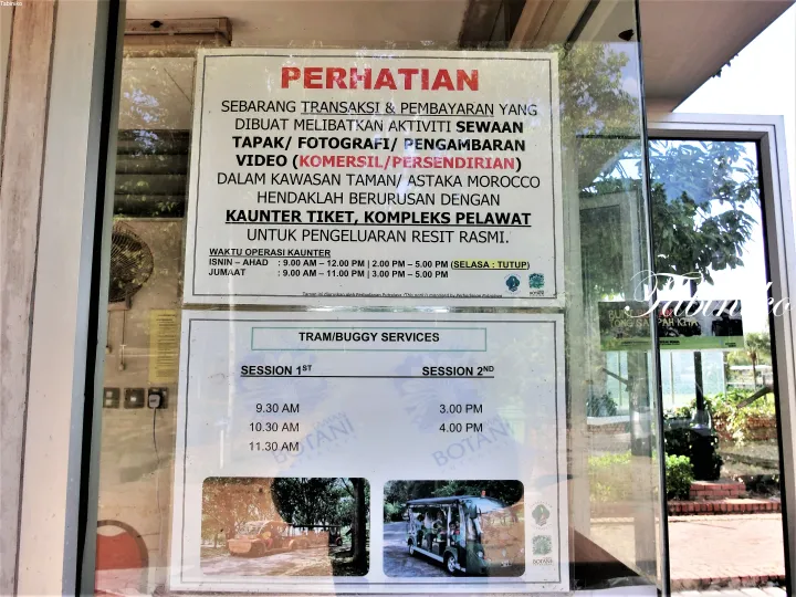Notice board at Putrajaya Botanical Garden detailing tram schedules and photography rental rules.