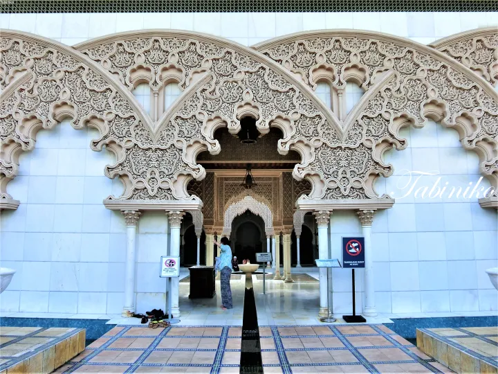 Intricate Moorish arches and detailed stonework at the entrance of the National Mosque in Kuala Lumpur.