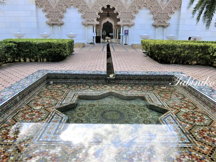 Ornate mosaic fountain and manicured hedges leading to the grand entrance of the Royal Museum of Islamic Art in Malaysia.