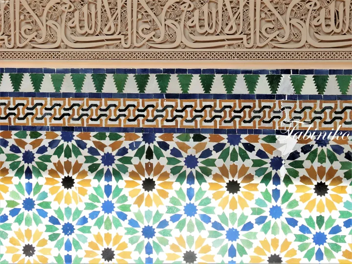 Intricate Islamic geometric tile patterns and Arabic calligraphy on a wall.