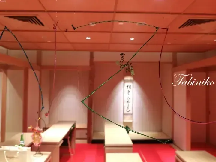 裝飾有懸掛飾物和掛軸的日式傳統餐廳，帶有Tabiniko標誌。