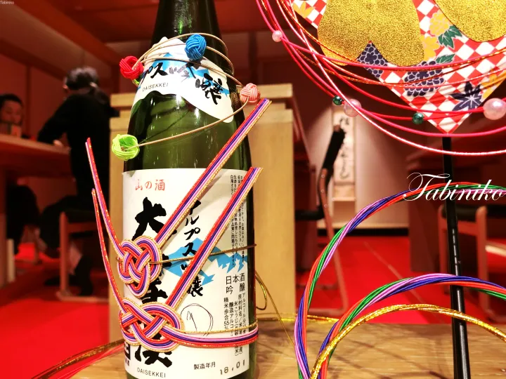 Decorated sake bottle with colorful ribbons and traditional ornaments on a table in a Japanese restaurant.
