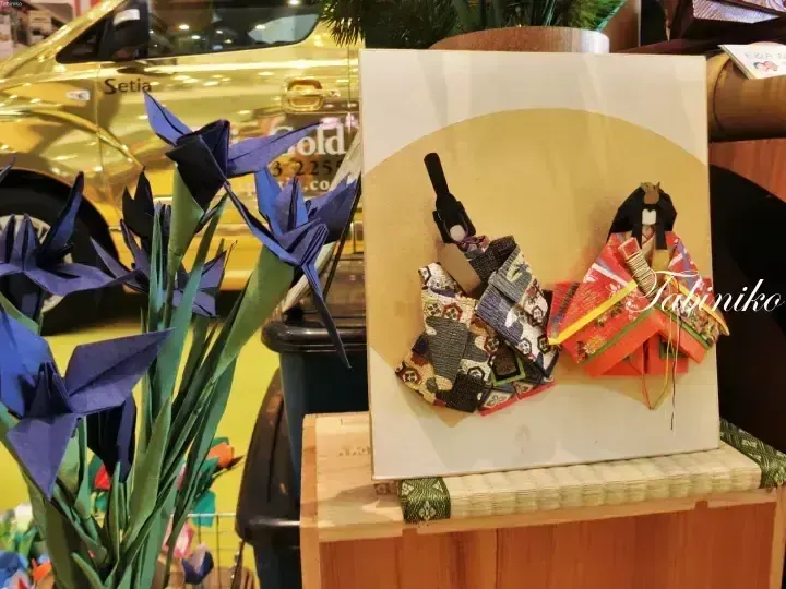 展示著藍色紙鶴和日本傳統人偶等彩色摺紙工藝品的場景。