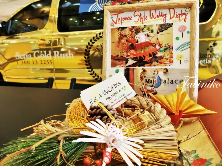 Japanese wedding display featuring a framed photo, traditional decorations, and a business card for E&A Works on a table.