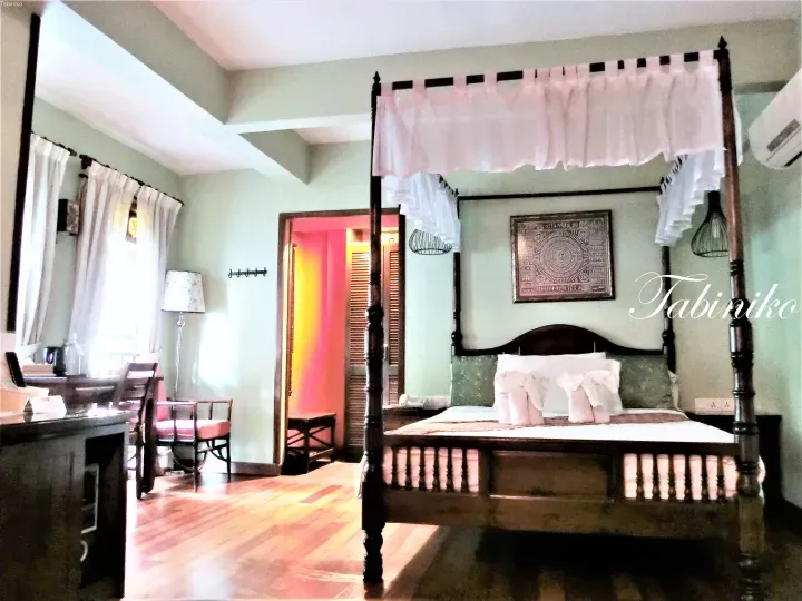 Cozy bedroom featuring a four-poster bed with pink canopy, wooden flooring, and a desk area in a Malaysia hotel room.