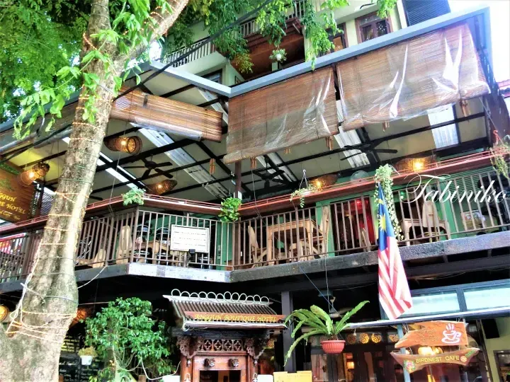 Anggun Boutique Hotel外观，设有木制阳台、悬挂植物和马来西亚国旗。