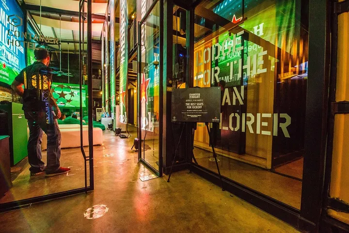 マレーシアのコンテナホテル、Heineken Champion Hostelの入り口。緑色の照明とプロモーション看板が特徴的な空間です。