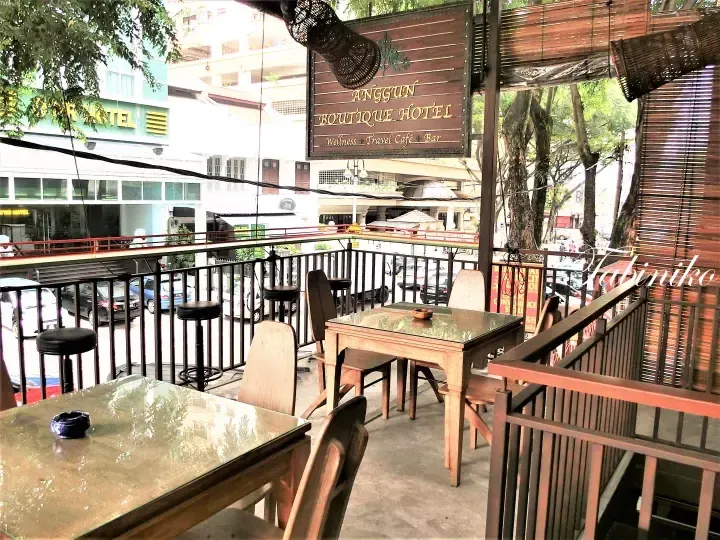 Outdoor terrace seating at Anggun Boutique Hotel with wooden tables overlooking a street in Malaysia.